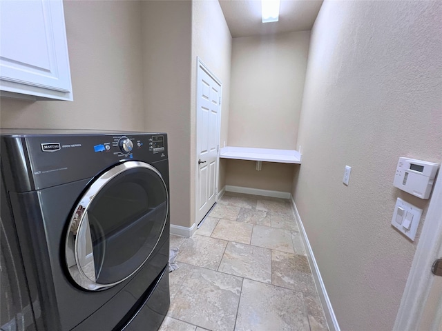 clothes washing area featuring cabinets and washer / dryer