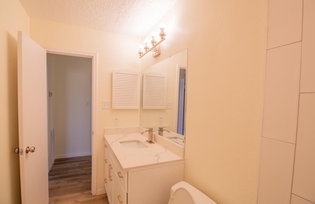 bathroom with hardwood / wood-style flooring, vanity, a textured ceiling, and toilet