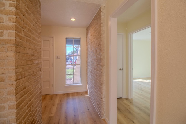 doorway with brick wall and light wood-type flooring