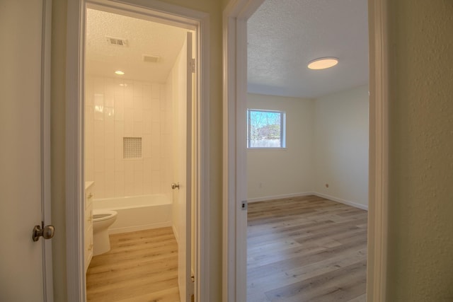 hallway featuring light hardwood / wood-style floors and a textured ceiling