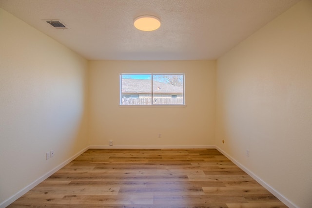 unfurnished room featuring a textured ceiling and light hardwood / wood-style floors