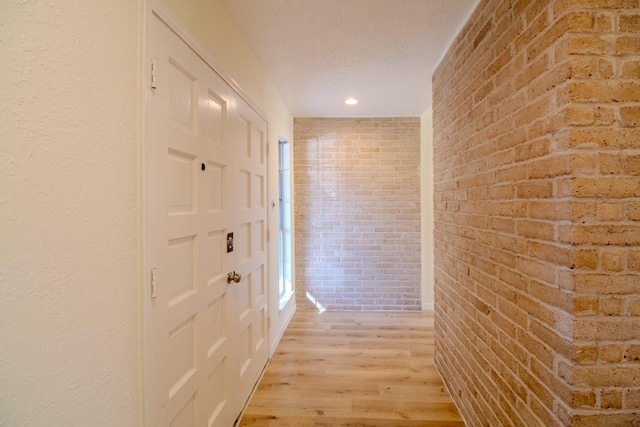 hallway with light hardwood / wood-style flooring and brick wall