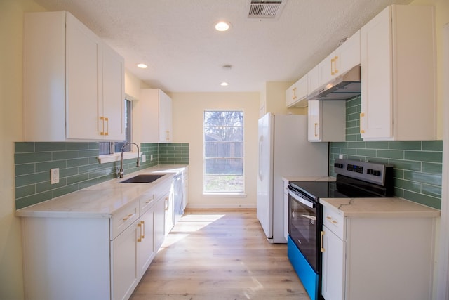 kitchen with sink, white cabinetry, stainless steel electric range oven, light hardwood / wood-style floors, and decorative backsplash