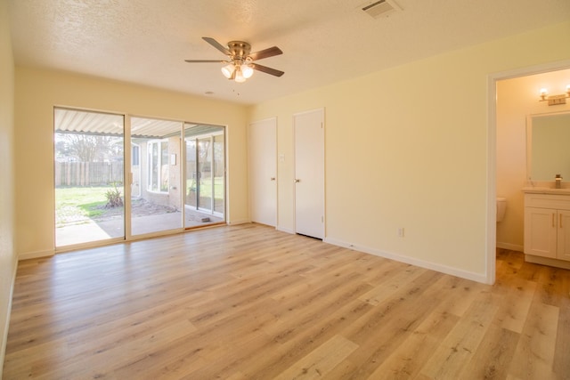 unfurnished bedroom featuring connected bathroom, a textured ceiling, light wood-type flooring, ceiling fan, and access to exterior