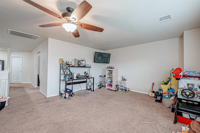 playroom with light carpet, ceiling fan, and a textured ceiling