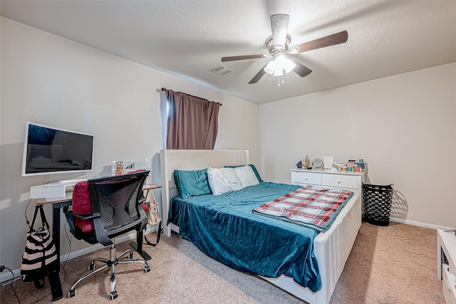 bedroom featuring ceiling fan, light colored carpet, and a textured ceiling