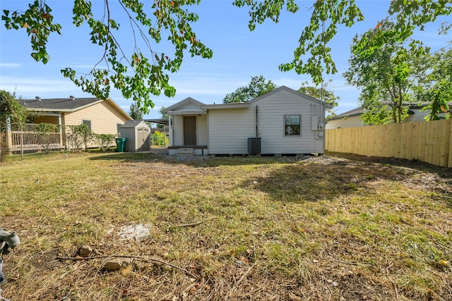 rear view of house with central AC, a storage shed, and a lawn