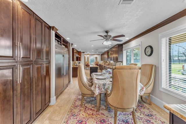 dining space featuring crown molding, light hardwood / wood-style flooring, a textured ceiling, and ceiling fan