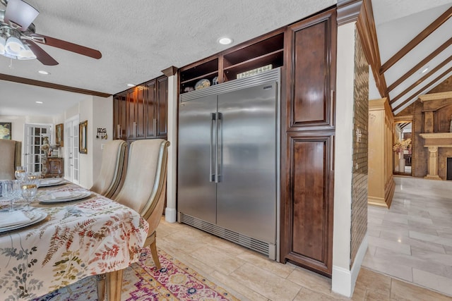 kitchen with built in fridge, ceiling fan, dark brown cabinetry, and a textured ceiling