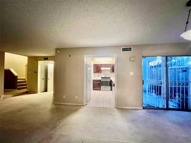 unfurnished living room with light colored carpet and a textured ceiling