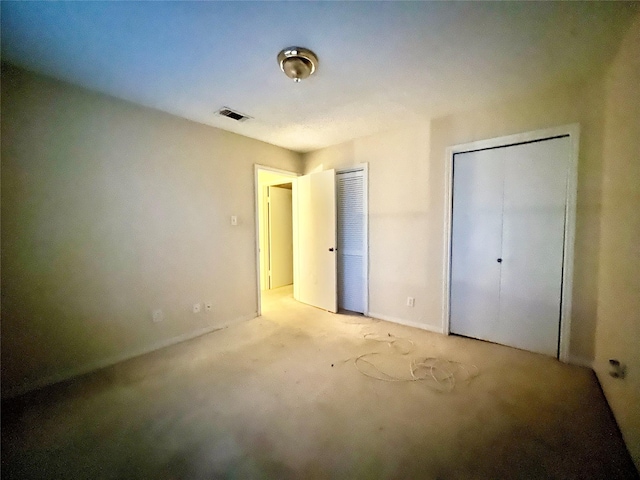 unfurnished bedroom with light carpet and two closets