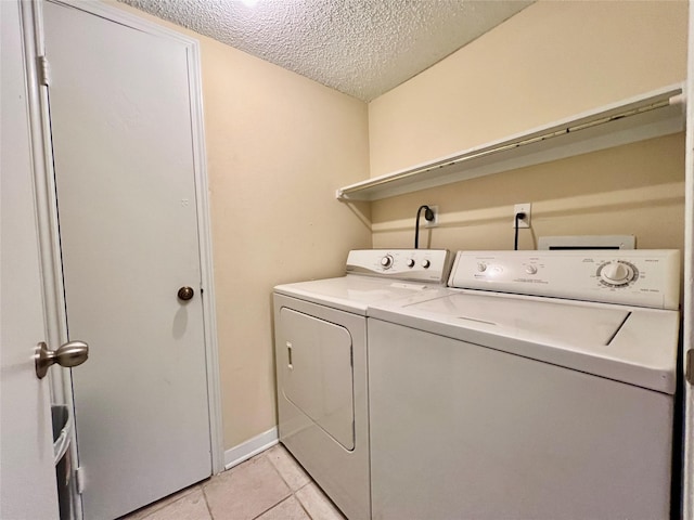 laundry room with light tile patterned flooring, washer and dryer, and a textured ceiling