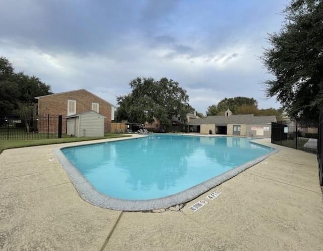 view of swimming pool featuring a storage shed and a patio area