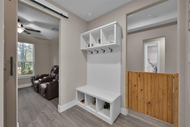 mudroom featuring light hardwood / wood-style floors, a barn door, and ceiling fan