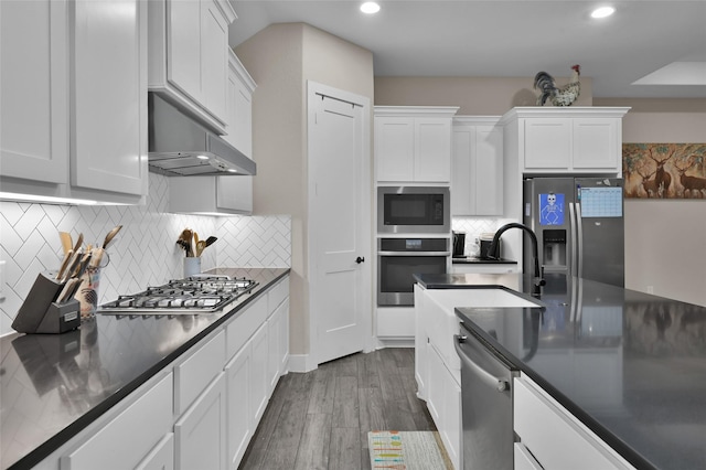 kitchen with hardwood / wood-style floors, backsplash, stainless steel appliances, and white cabinets