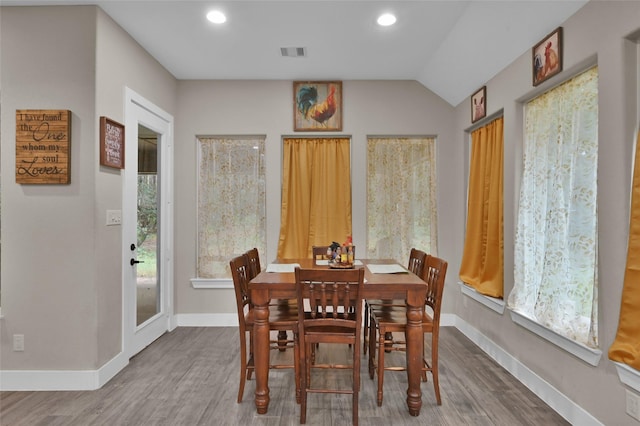 dining room featuring vaulted ceiling, plenty of natural light, and hardwood / wood-style floors