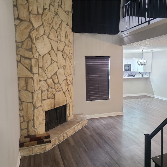 unfurnished living room with a stone fireplace, hardwood / wood-style floors, and a textured ceiling