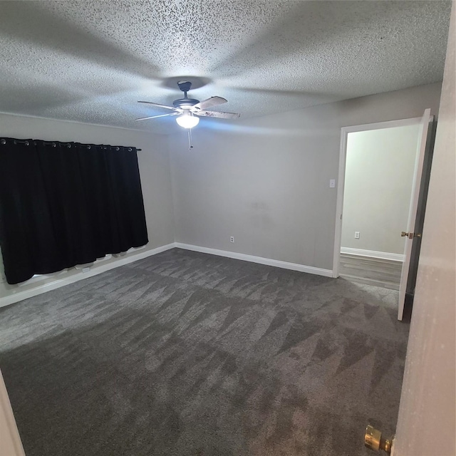 unfurnished room with ceiling fan, dark carpet, and a textured ceiling