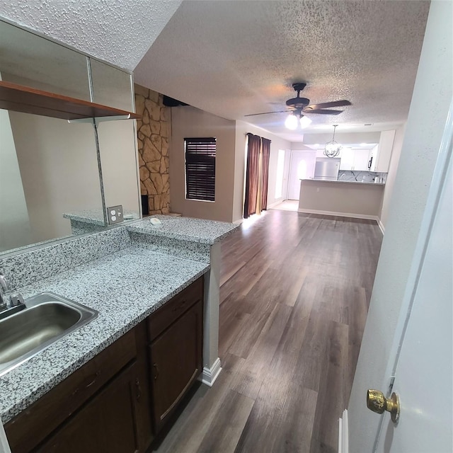 kitchen featuring ceiling fan, wood-type flooring, sink, and a textured ceiling