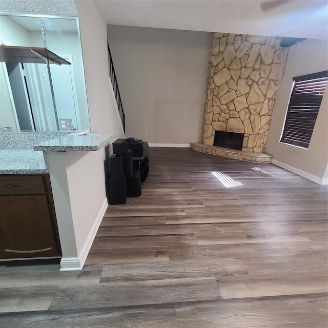 unfurnished living room with dark hardwood / wood-style floors, a textured ceiling, and a fireplace