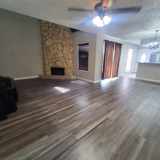 unfurnished living room with dark hardwood / wood-style floors, a fireplace, ceiling fan with notable chandelier, and a textured ceiling