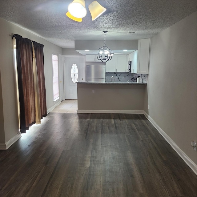 kitchen featuring white cabinetry, dark hardwood / wood-style flooring, stainless steel fridge, and kitchen peninsula