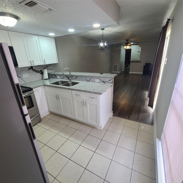 kitchen featuring sink, white cabinetry, light stone countertops, decorative light fixtures, and kitchen peninsula