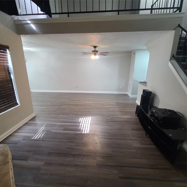 living room featuring ceiling fan, dark hardwood / wood-style flooring, and a textured ceiling