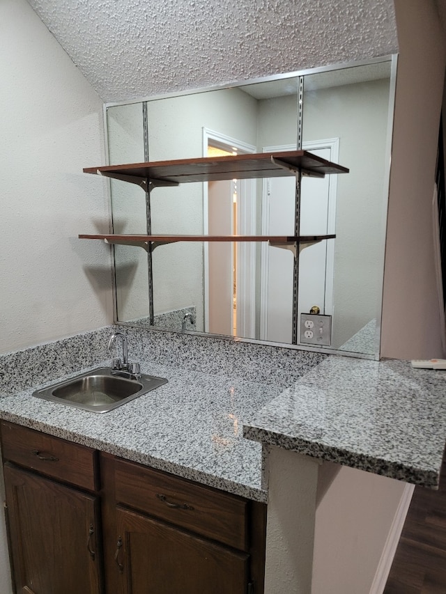 kitchen with light stone counters, sink, and dark wood-type flooring