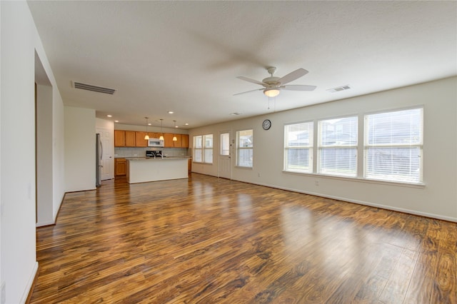 unfurnished living room featuring a textured ceiling, dark hardwood / wood-style floors, and ceiling fan