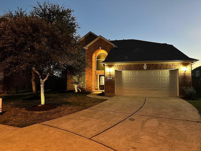 traditional-style house featuring a garage, brick siding, driveway, and a shingled roof