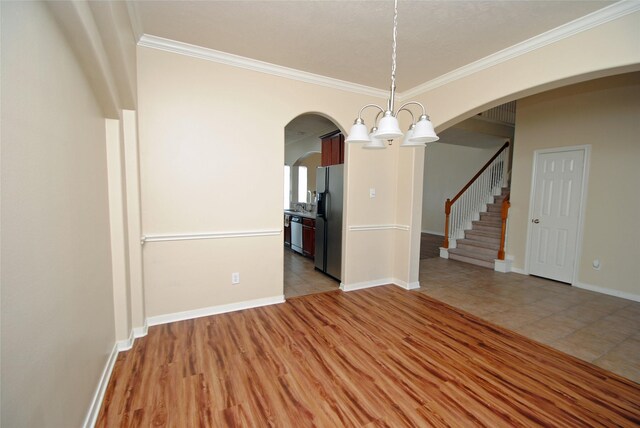 unfurnished dining area with a notable chandelier, ornamental molding, and light wood-type flooring