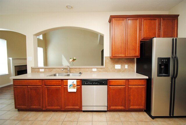 kitchen with appliances with stainless steel finishes, sink, light tile patterned floors, and backsplash