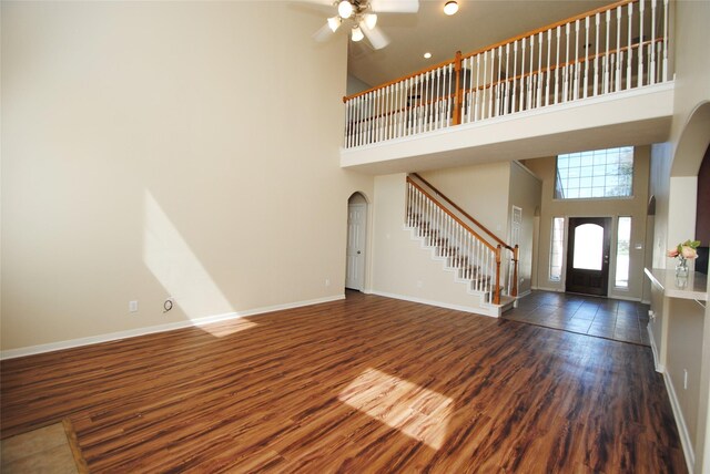 foyer entrance featuring ceiling fan, a towering ceiling, and dark hardwood / wood-style flooring