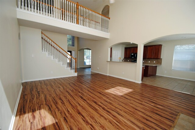 unfurnished living room featuring dark wood-type flooring and a high ceiling