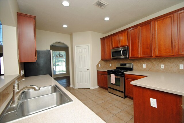 kitchen featuring appliances with stainless steel finishes, sink, light tile patterned floors, and backsplash