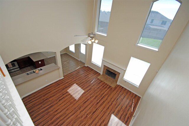 unfurnished living room featuring sink, dark hardwood / wood-style floors, a towering ceiling, ceiling fan, and a fireplace