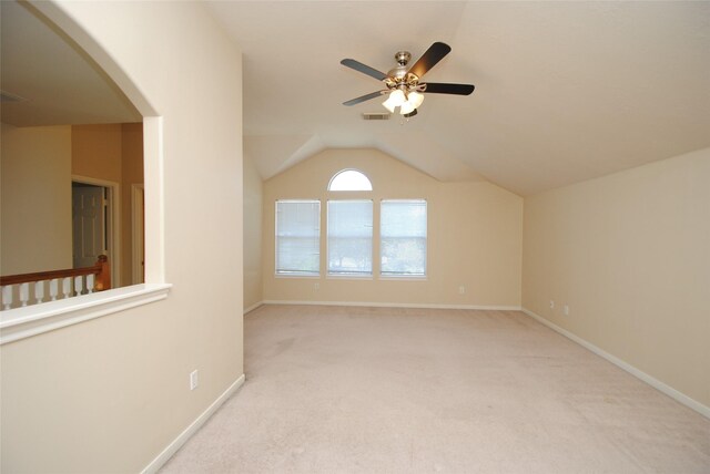 carpeted spare room featuring vaulted ceiling and ceiling fan