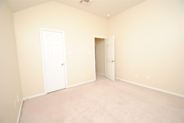 empty room featuring vaulted ceiling and light carpet