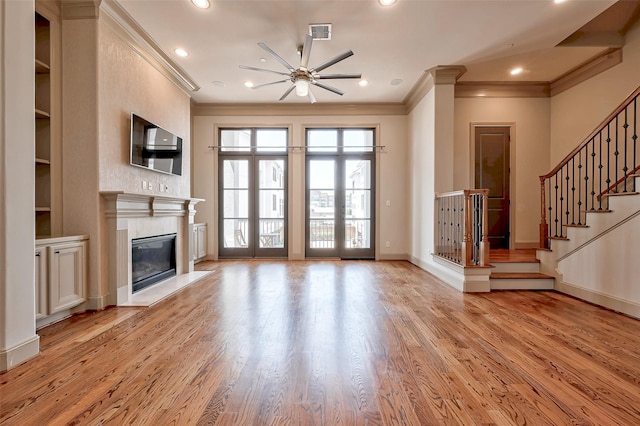 unfurnished living room featuring a high end fireplace, ornamental molding, and light wood-type flooring