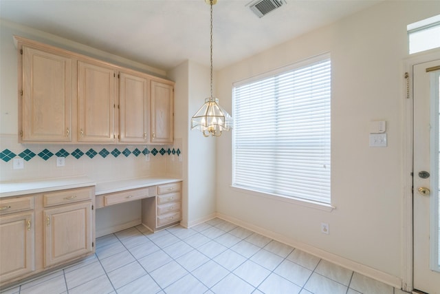 kitchen with built in desk, pendant lighting, backsplash, and light brown cabinetry