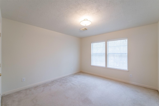 carpeted empty room featuring a textured ceiling