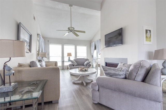 living room featuring light hardwood / wood-style flooring, high vaulted ceiling, and ceiling fan