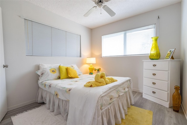 bedroom featuring ceiling fan, a textured ceiling, and light wood-type flooring