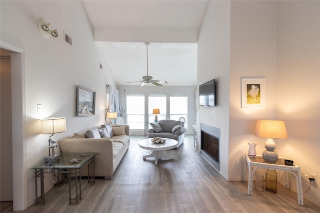 living room with hardwood / wood-style floors, beam ceiling, high vaulted ceiling, and ceiling fan