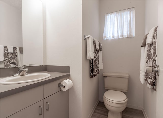 bathroom with vanity, toilet, and hardwood / wood-style floors