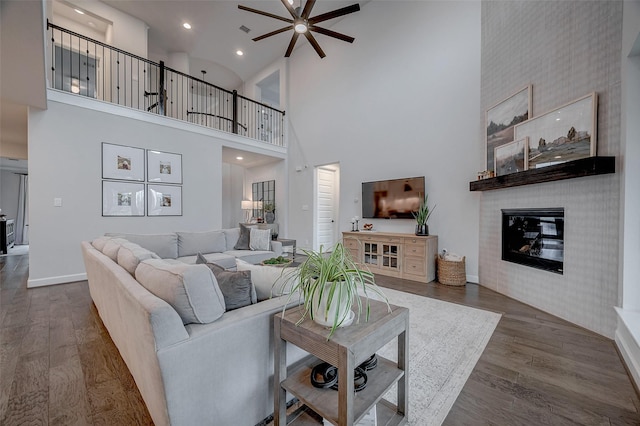 living room with a ceiling fan, a fireplace, baseboards, and dark wood-style flooring