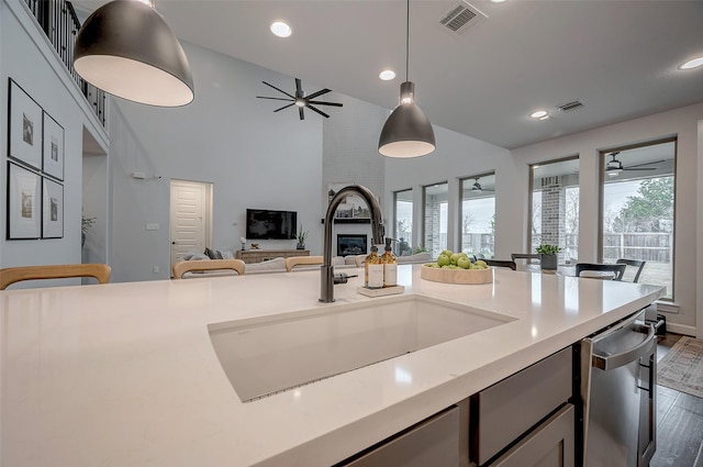 kitchen featuring light countertops, open floor plan, a large fireplace, a sink, and dishwasher