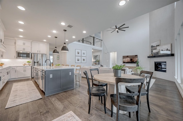 interior space with a fireplace, visible vents, dark wood finished floors, and a ceiling fan