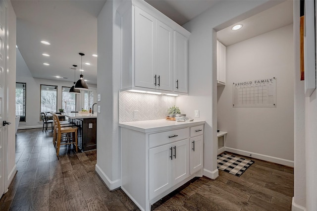 interior space with baseboards, decorative backsplash, pendant lighting, and dark wood-style flooring